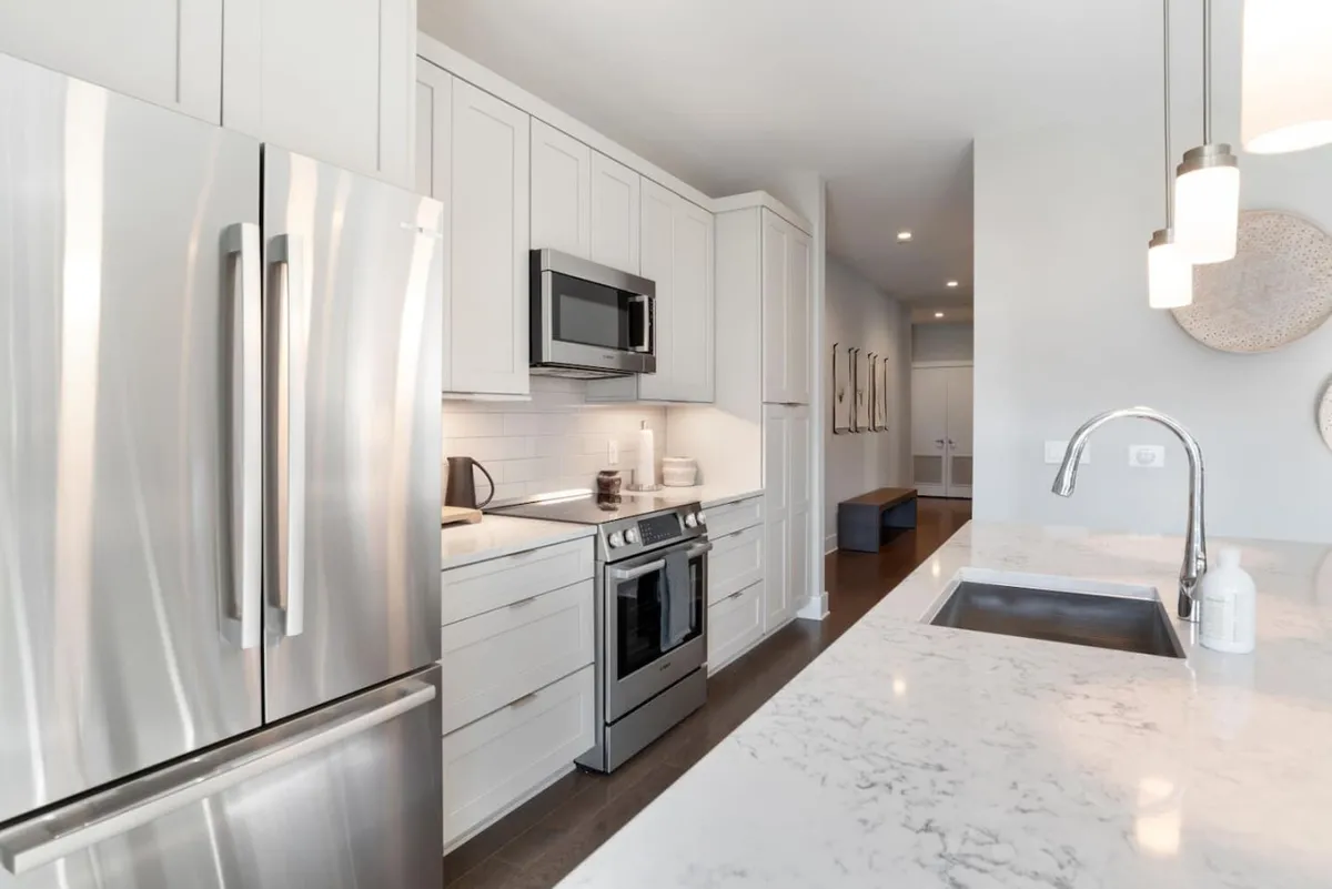 A functional and stylish kitchen with stainless steel appliances, marble countertops, and modern cabinetry. The layout encourages both cooking and socializing, with a bright, clean aesthetic that suits family gatherings or hosting friends for dinner.