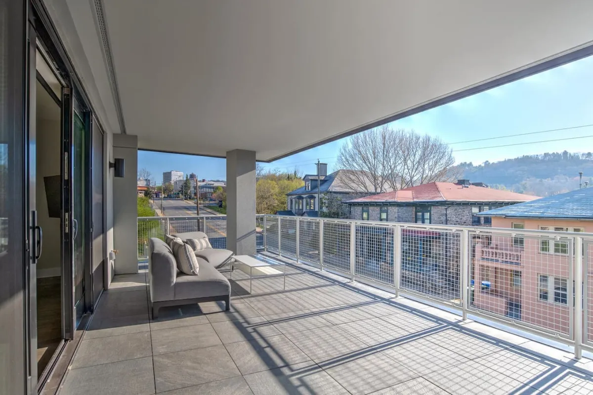 A private balcony with comfortable seating overlooks a vibrant street and the surrounding architecture. The view connects the living space to the pulse of downtown Asheville, inviting residents to step outside and enjoy the city’s culture, dining, and nightlife.
