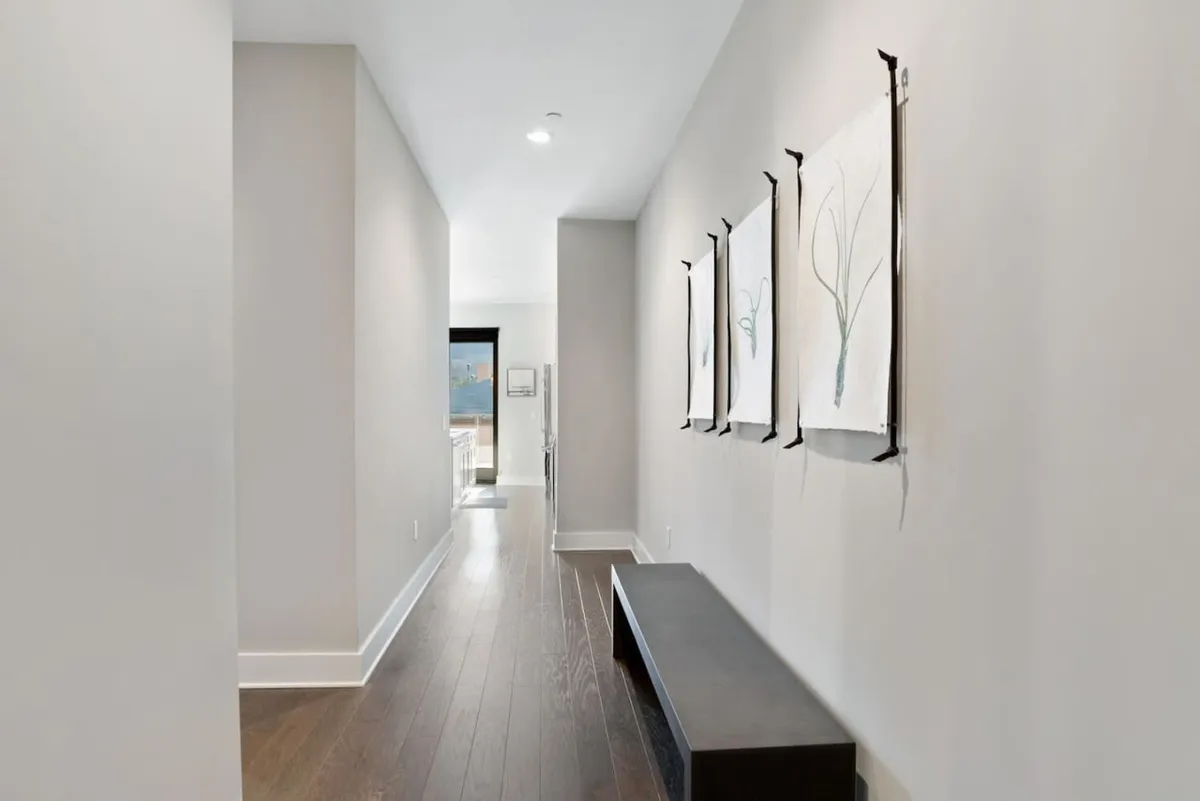 An inviting entryway with artistic wall decor, bench seating, and a view through a doorway leading towards the main living area. The entry feels modern and sets a refined tone for the rest of the home.