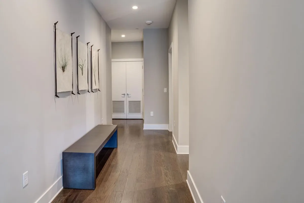 A bright lobby or entryway featuring a wooden bench, modern artwork on the wall, and double doors. The space exudes a welcoming and professional atmosphere, suggesting attentive management and a secure, well-maintained environment.